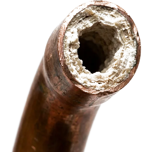 Cut-open copper pipe showing its bore narrowed by mineral scale